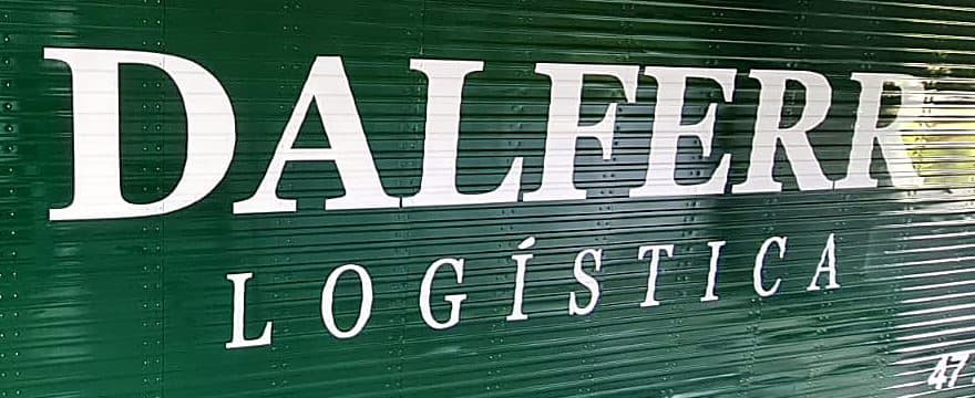 Detalhe das letras serifadas brancas DALFERR LOGÍSTICA sobre o verde frisado