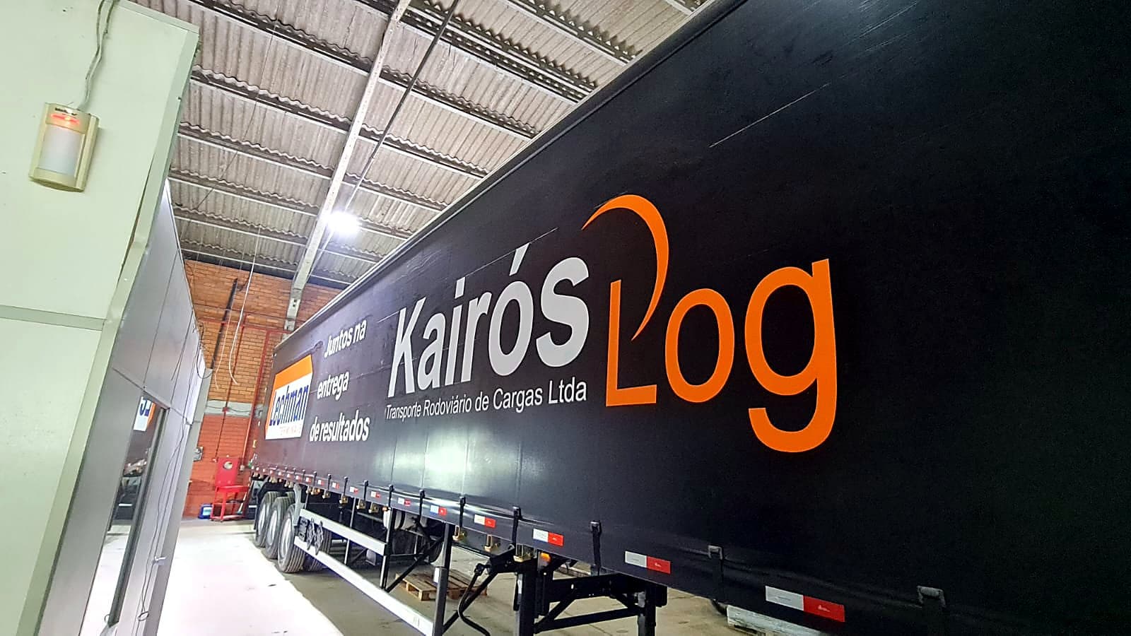 Carreta sider preta da Kairós Log com logomarca e a frase Juntos na entrega de resultados