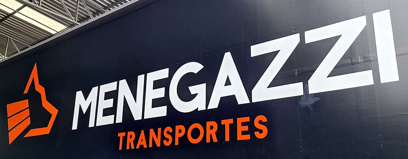 Detalhe do símbolo laranja e do nome Menegazzi pintados na lona preta